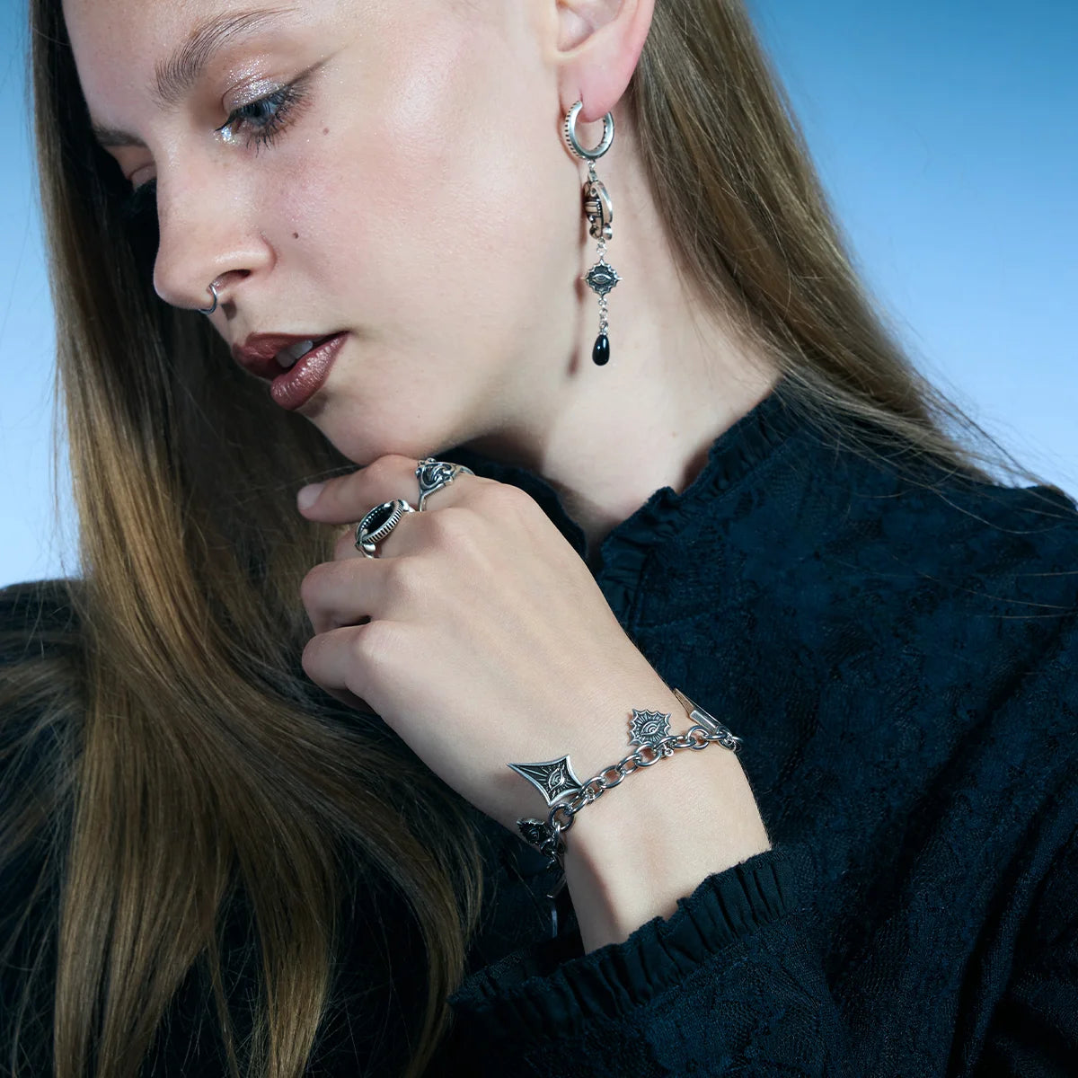 Antiqued silver-tone Unblinking Procession Bracelet worn in a downward-looking portrait, highlighting its substantial chain and moving charms.