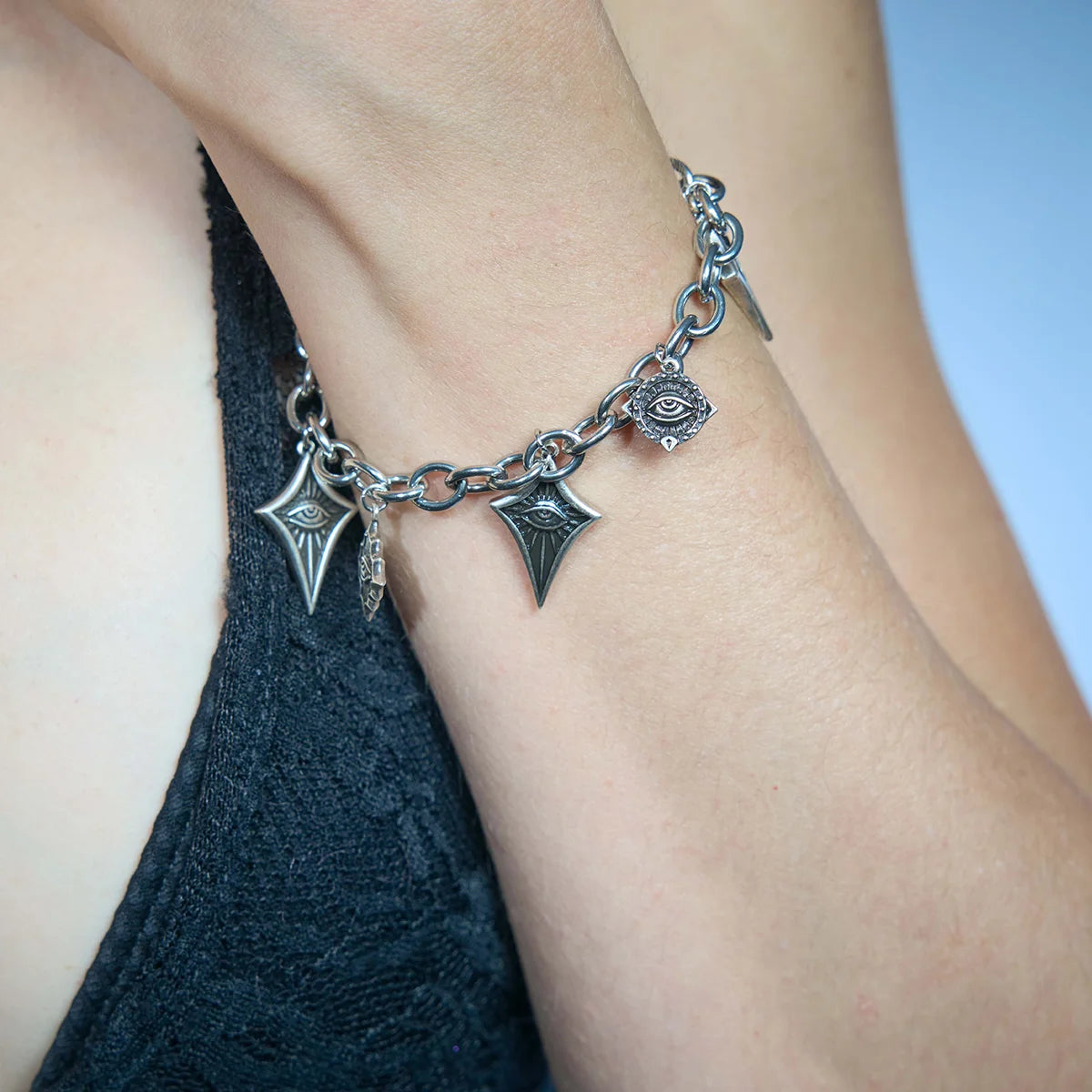 Close-up of an antiqued silver-tone Unblinking Procession Bracelet worn on the wrist with freely suspended sculpted eye charms.