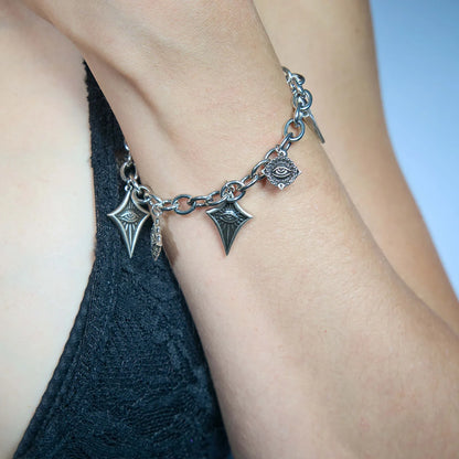 Close-up of an antiqued silver-tone Unblinking Procession Bracelet worn on the wrist with freely suspended sculpted eye charms.