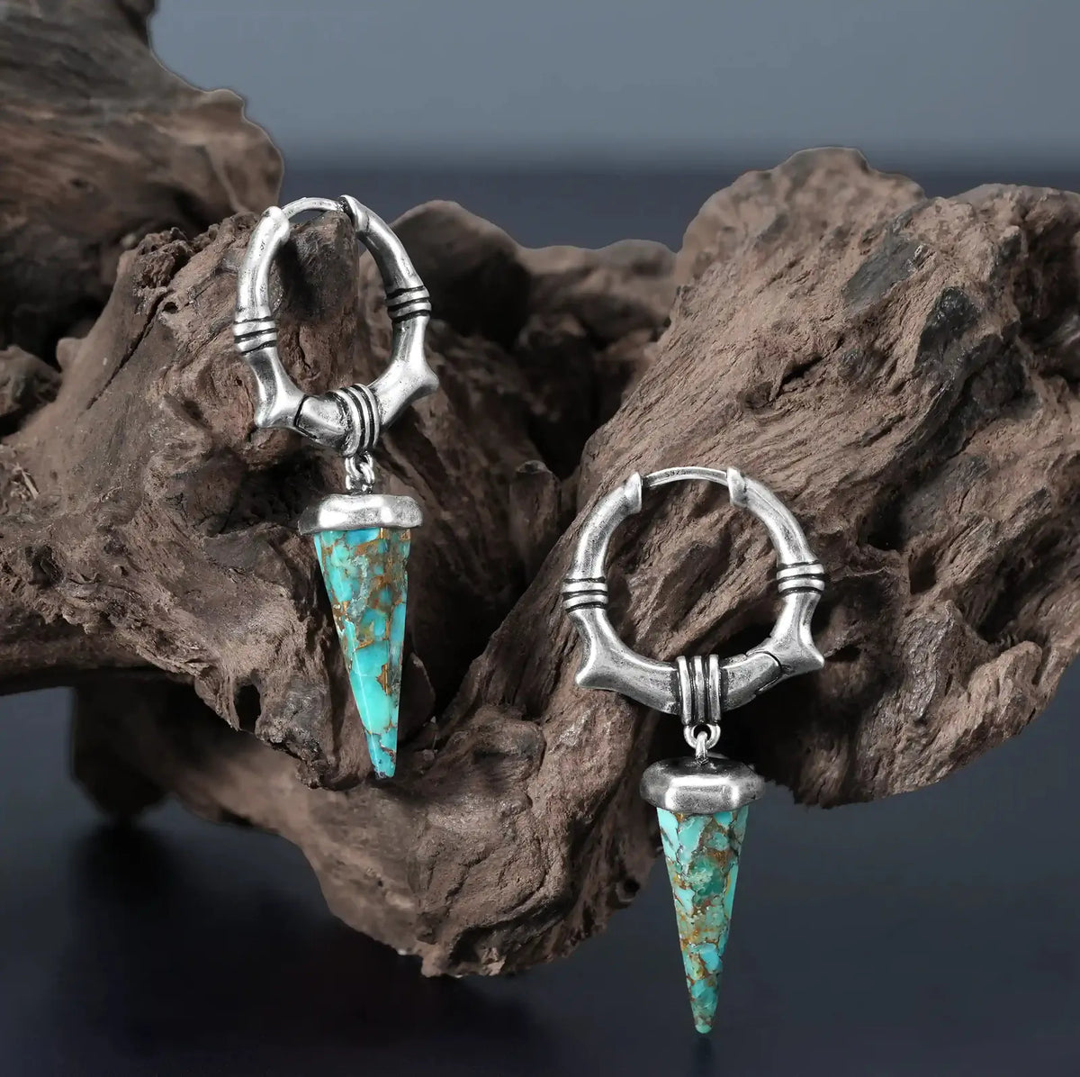 Unearthed Spike Earrings in 925 sterling silver, pair displayed on weathered driftwood to contrast the turquoise stone and ox