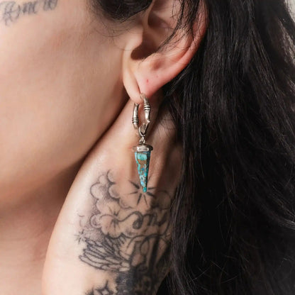 Unearthed Spike Earrings in 925 sterling silver, worn in a tattooed ear close-up, showing the turquoise stone spike and textu