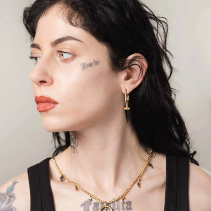 Model wearing gold Unearthed Spike Earrings with obsidian spike pendants and antiqued brass finish
