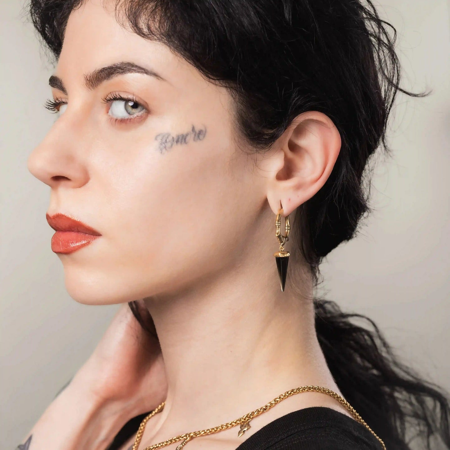 Gold Unearthed Spike Earrings styled on model with dark stone drops and sharp relic silhouette