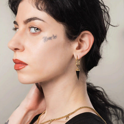 Gold Unearthed Spike Earrings styled on model with dark stone drops and sharp relic silhouette