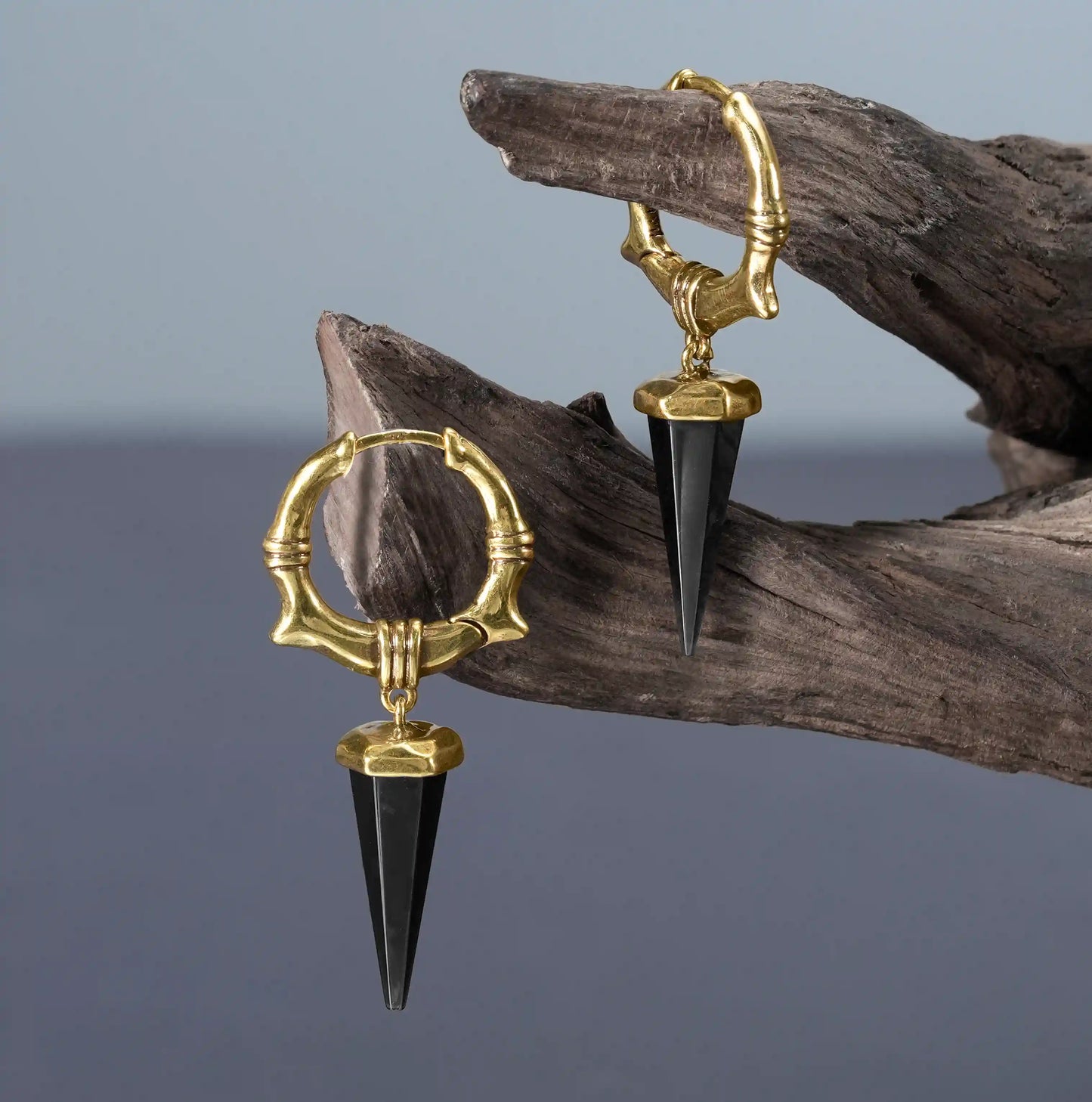 Gold Unearthed Spike Earrings displayed on driftwood with black obsidian spike drops