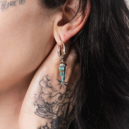 Model wearing silver Unearthed Spike Earrings with turquoise spike drops and antiqued hoop detail
