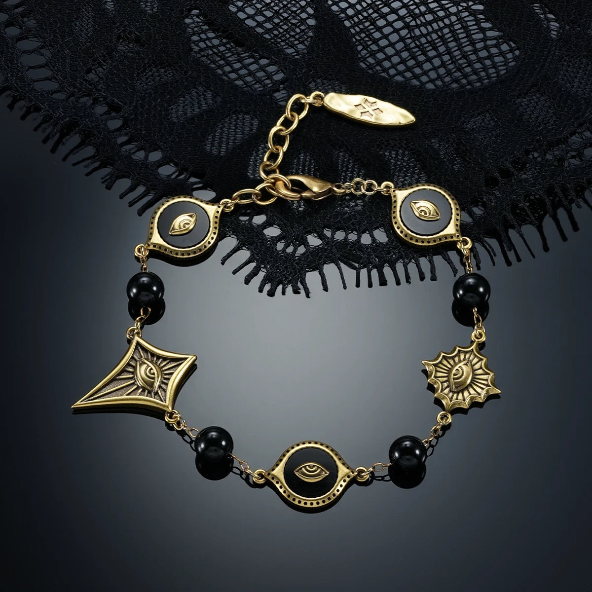 Gold-tone Unseen Orbit Bracelet displayed in a circular arrangement against black lace on a dark reflective surface.