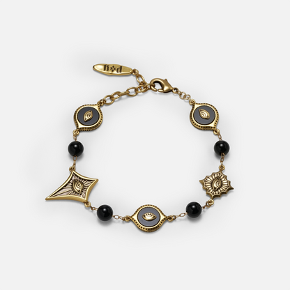 Gold-tone Unseen Orbit Bracelet displayed in a circular arrangement with black obsidian beads and sculpted eye medallions.