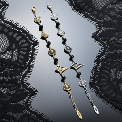 Antiqued silver- and gold-tone Unseen Orbit Bracelets displayed together against black lace on a dark reflective surface.