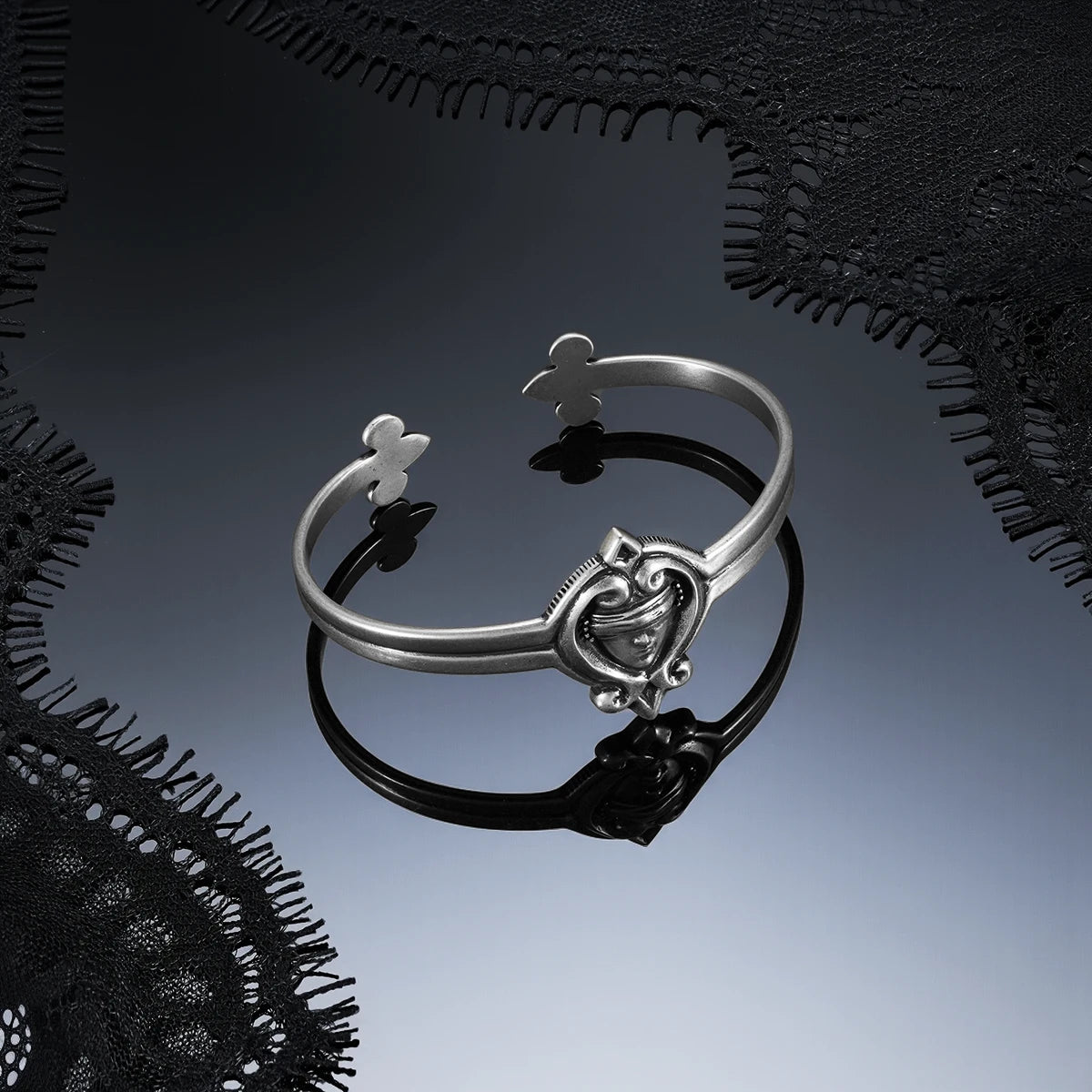 Antiqued silver-tone Veiled Seer Cuff Bracelet displayed on a dark reflective surface against black lace.