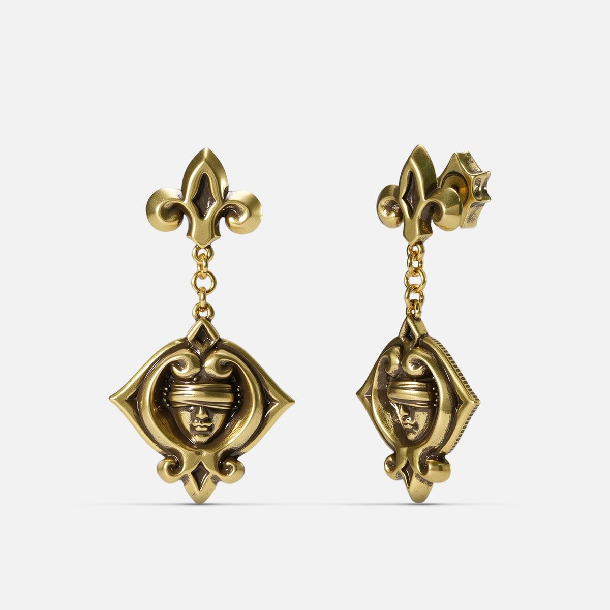 Gold-tone Veiled Seer Drop Earrings shown from front and side views with blindfolded face motifs and pointed eye-shaped frames.