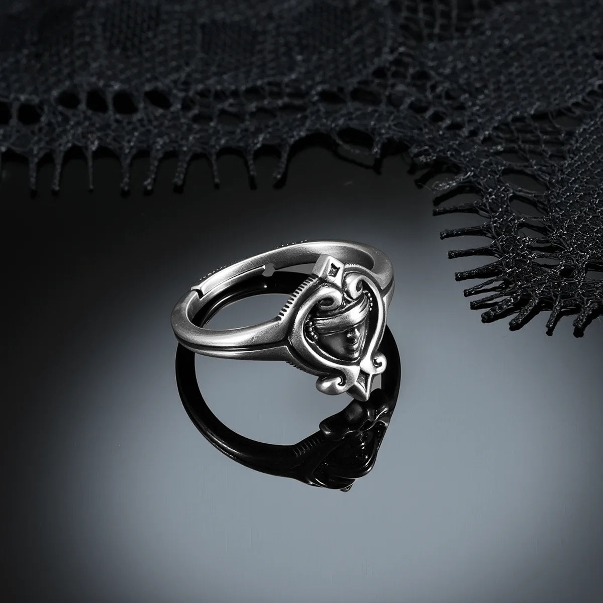 Antiqued silver Veiled Seer Ring displayed from an angled view on a dark reflective surface beneath black lace.