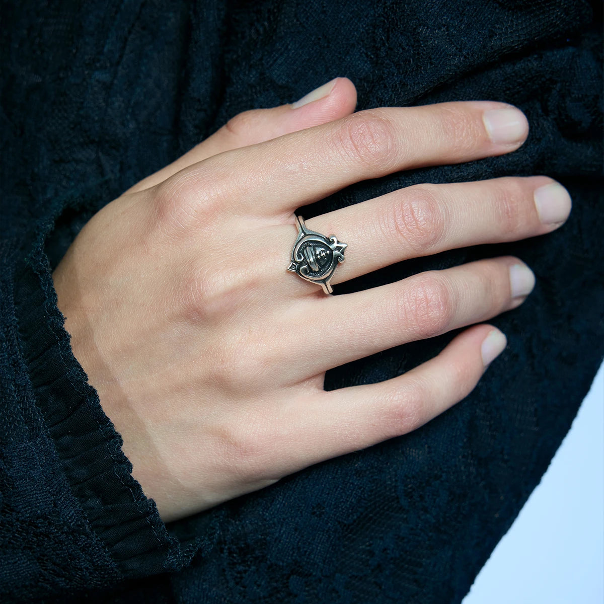 Close-up of an antiqued silver Veiled Seer Ring worn on the hand, highlighting the blindfolded face inside a pointed frame.