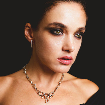 Model wearing a silver claw hoop earring paired with a matching chain necklace