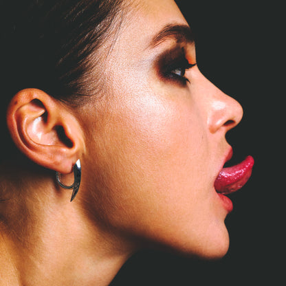 Close profile view of a model wearing a silver claw hoop earring on the ear