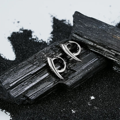 Pair of silver Venom Claw hoop earrings displayed on black crystal