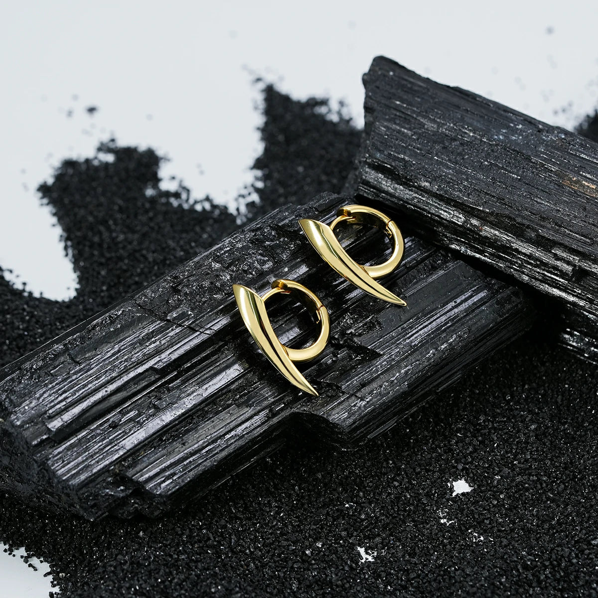 Pair of gold Venom Claw hoop earrings displayed on black crystal