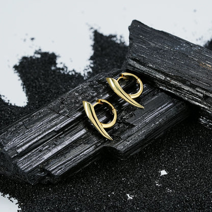 Pair of gold Venom Claw hoop earrings displayed on black crystal