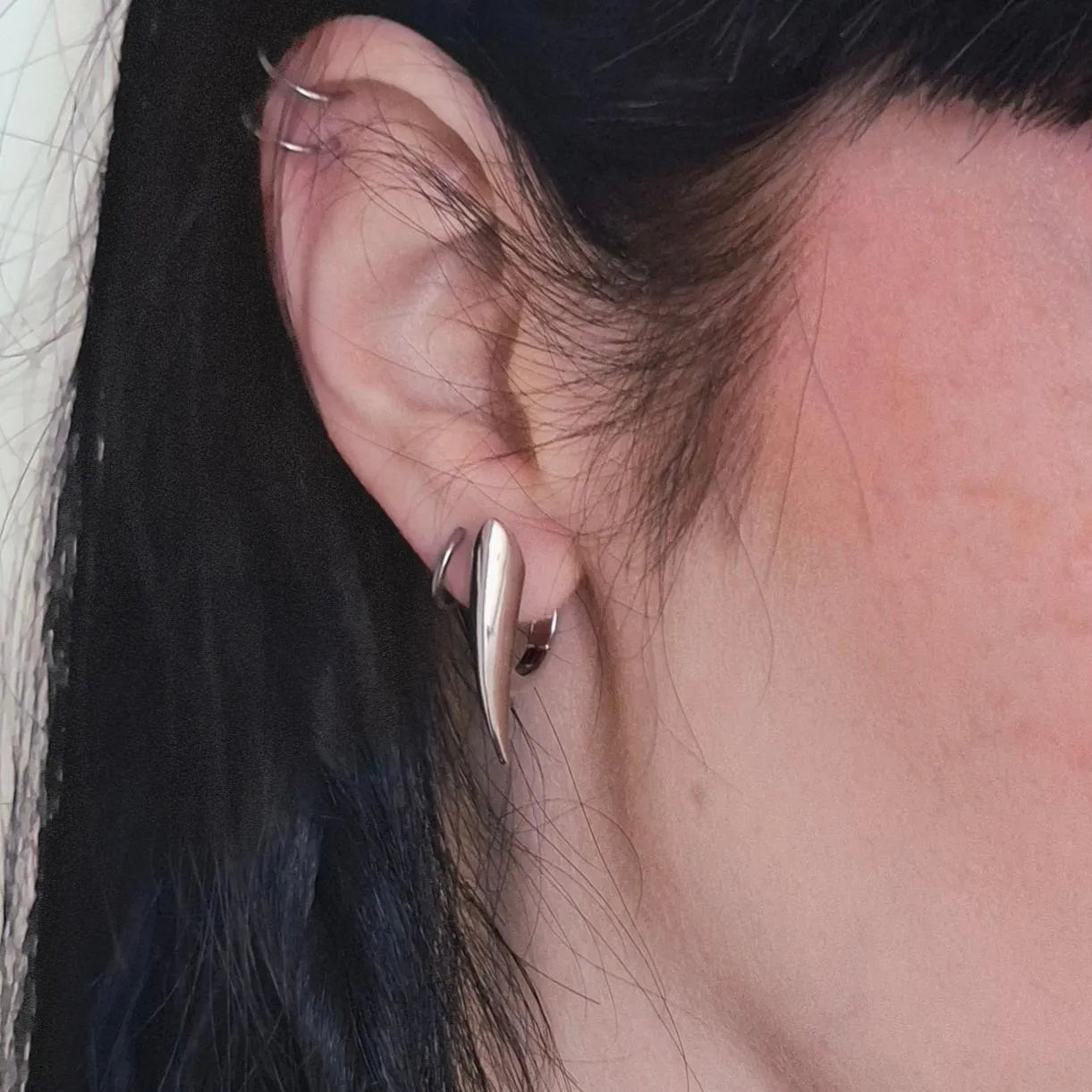 Model wearing silver Venom Claw Earrings with curved fang-shaped hoop design