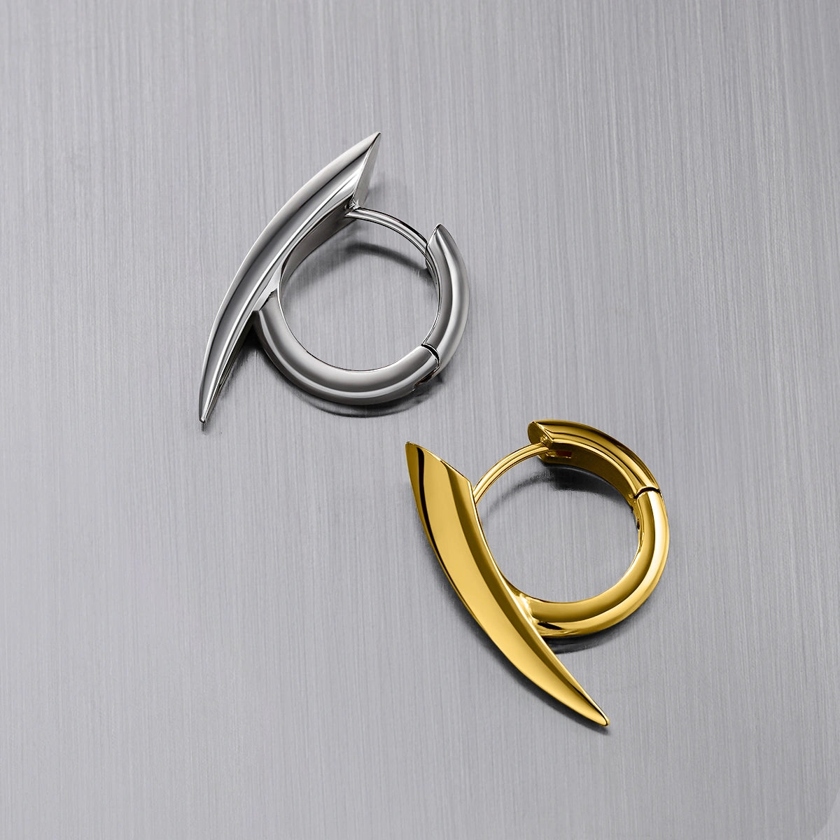Silver-tone and gold-tone claw hoop earrings placed together on a brushed metal surface