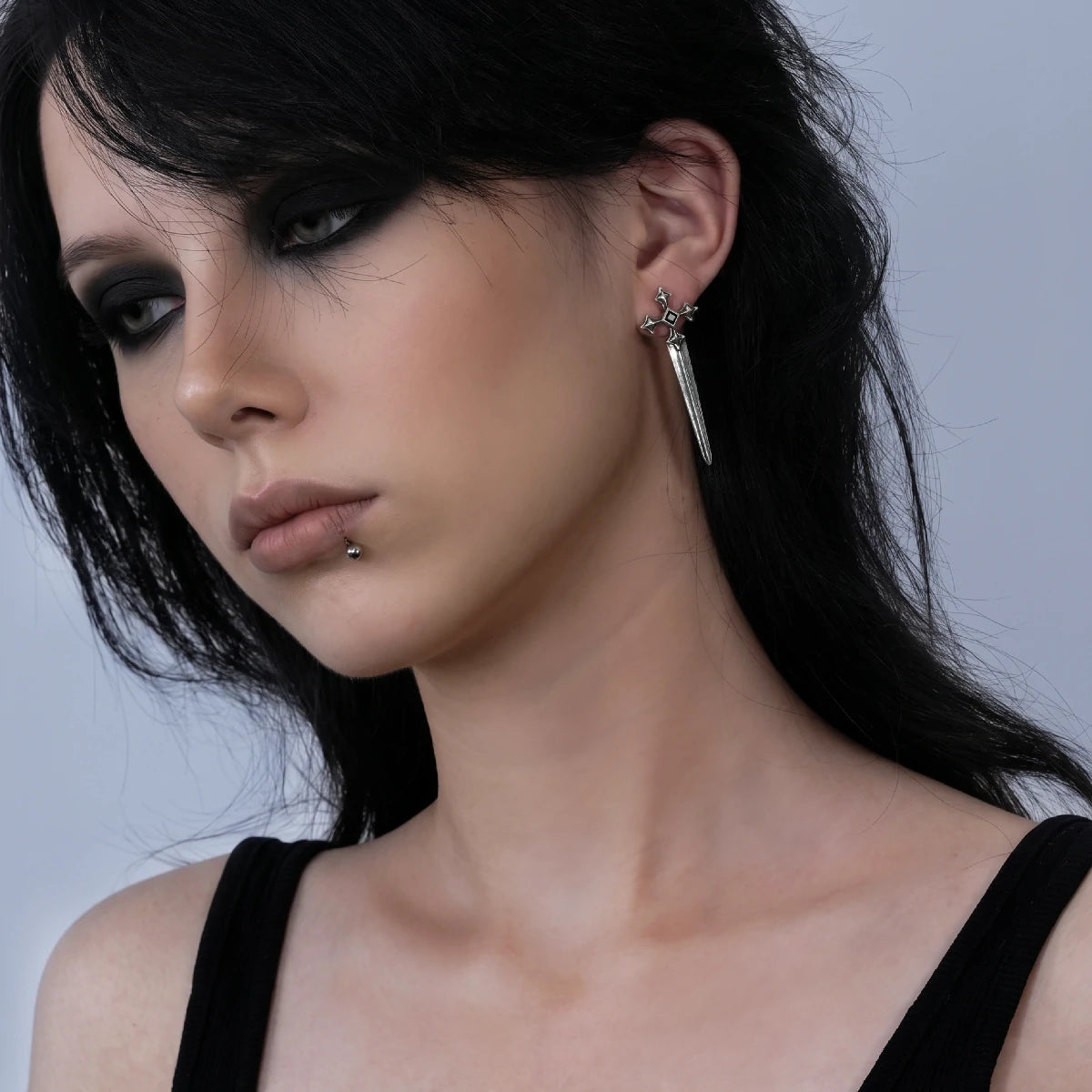 Vesper Blade Stud Earrings in antiqued silver worn on the ear in a close side-profile portrait with dark hair.
