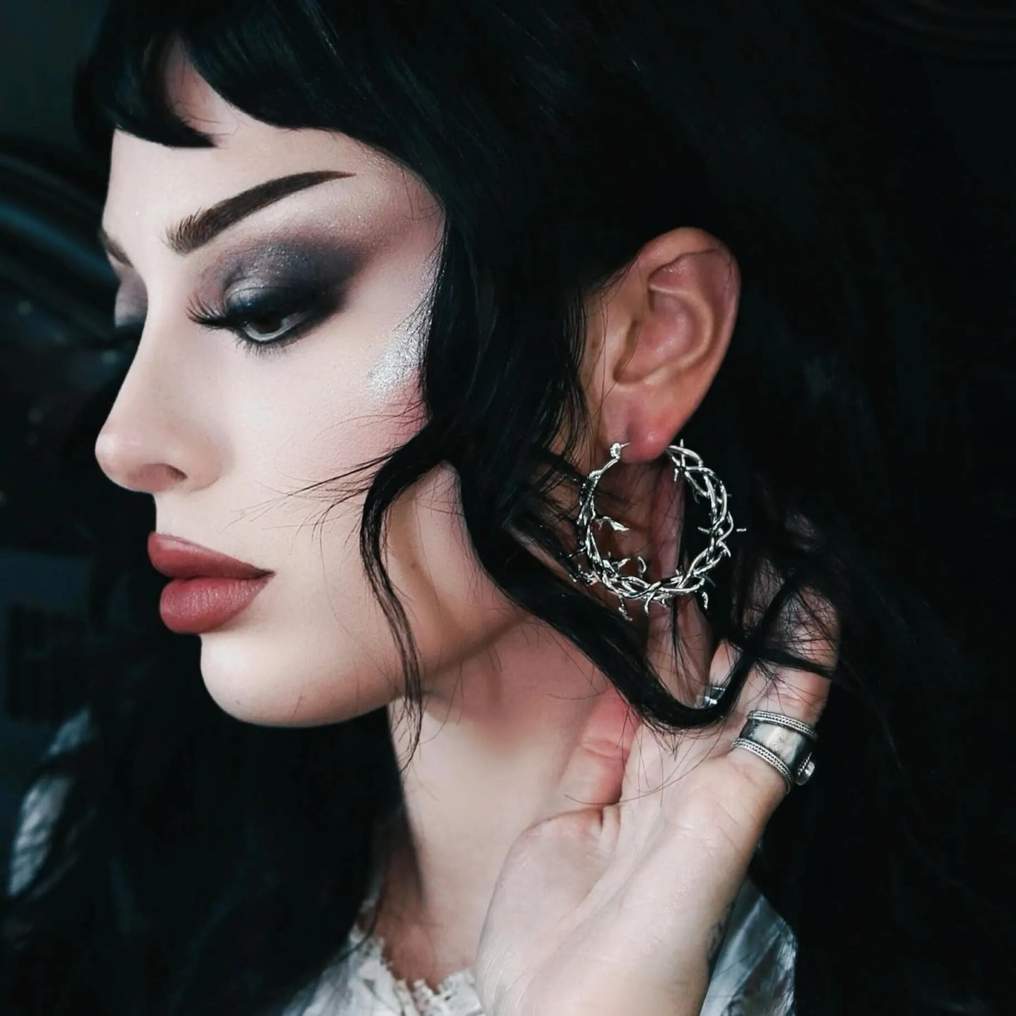 Close-up of a person wearing hoop earrings with a dark background