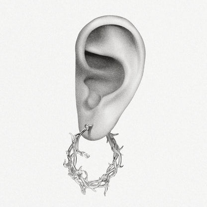 Silver-tone Vine Whispers thorn hoop earring positioned on an illustrated earlobe