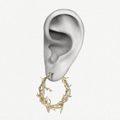 Gold-tone Vine Whispers thorn hoop earring positioned on an illustrated earlobe