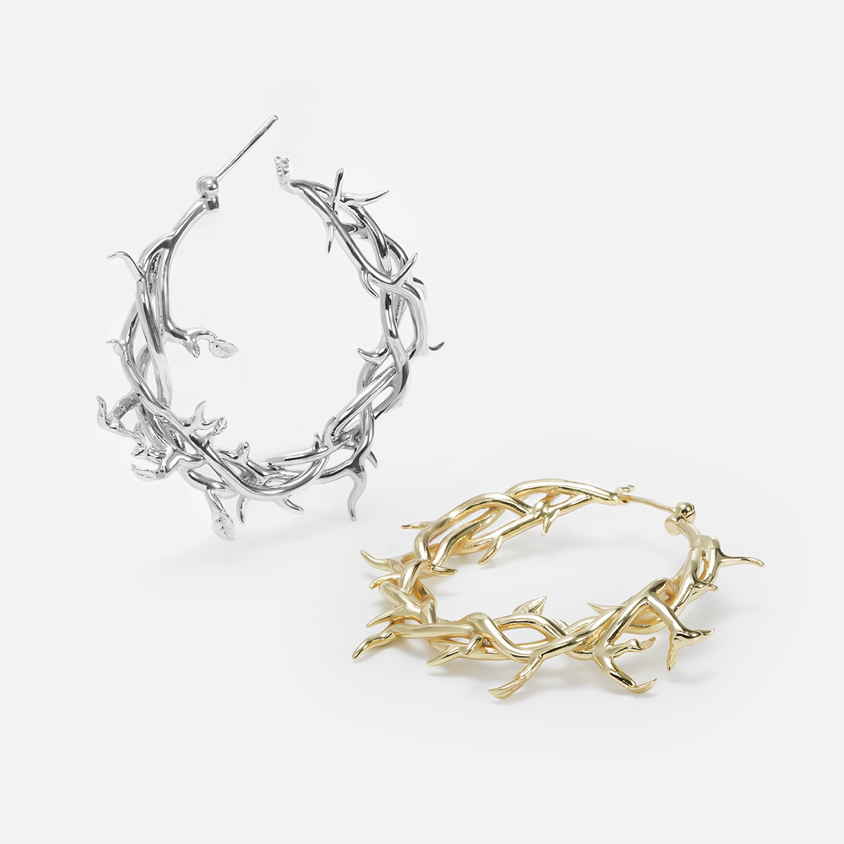 Two vine and thorn hoop earrings shown side by side in silver-tone and gold-tone finishes