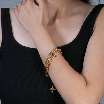 Vowbound Chain Bracelet in antiqued 18K gold worn on the wrist with the hand raised near the shoulder over a black top.