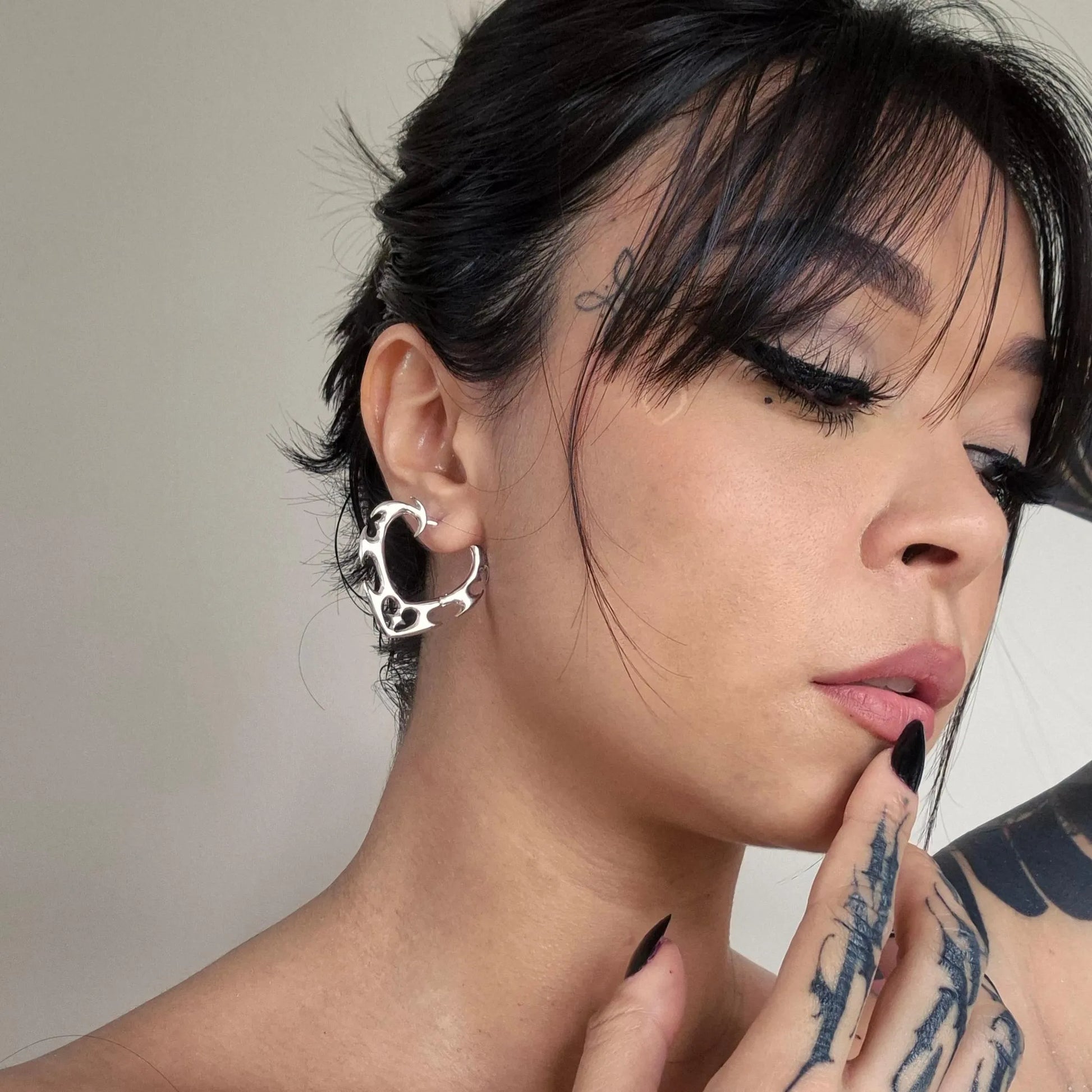 Silver Wild Heart Earrings styled on model with thorned heart silhouette and gothic romantic jewelry look