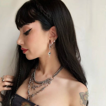 Winged Heartburst Earrings in 925 sterling silver, worn in side profile with black bangs and layered gothic silver necklaces.