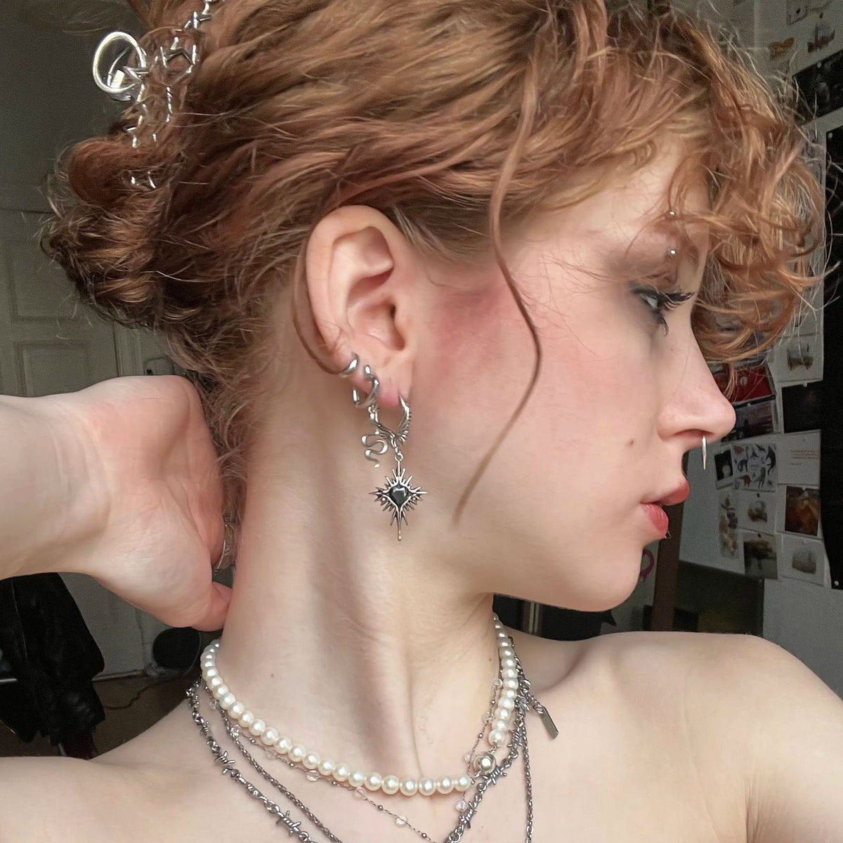 Winged Heartburst Earrings in 925 sterling silver, worn with a curly updo, layered pearl necklaces, and a mixed silver ear st