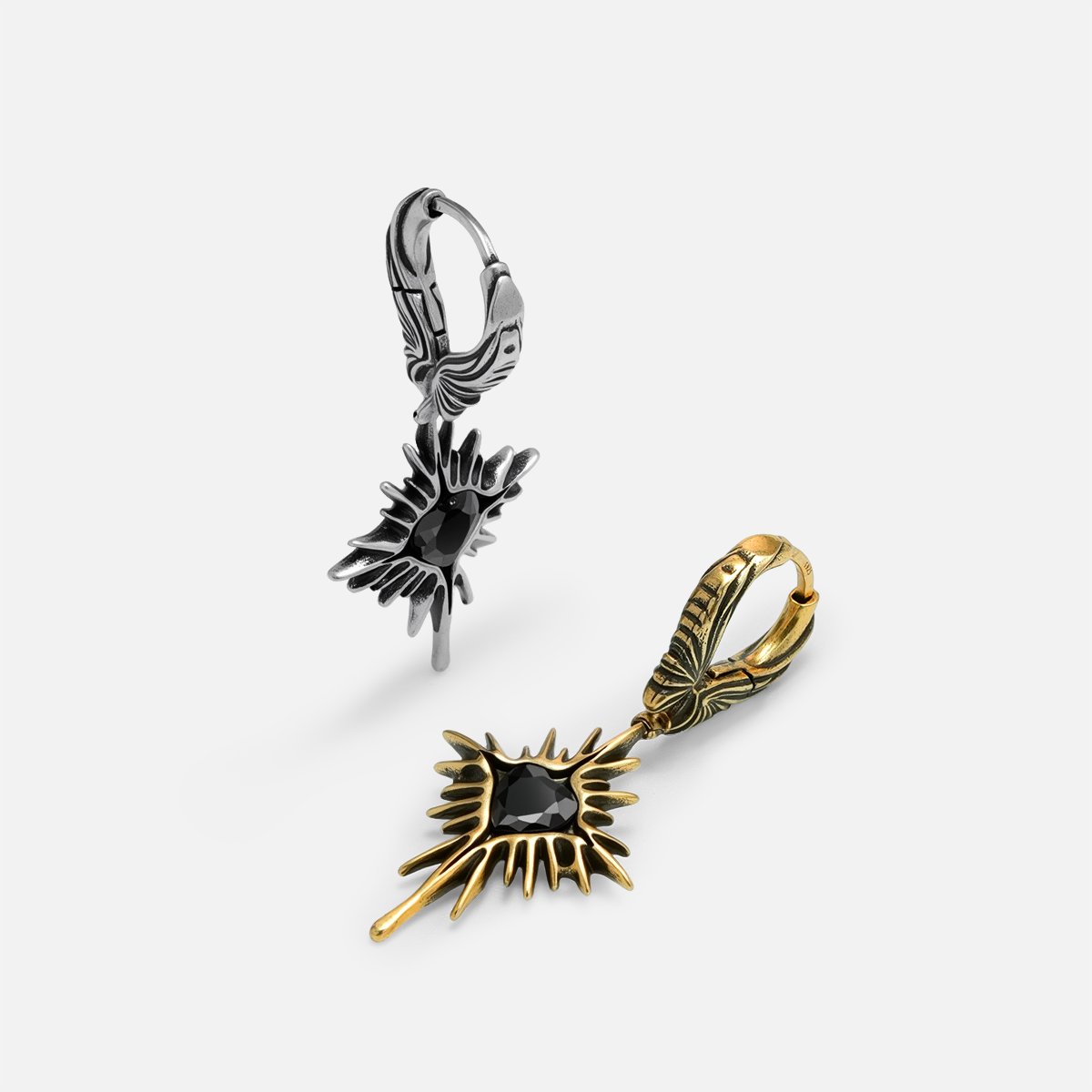 Silver and gold-tone Winged Heartburst hoop earrings arranged upright and flat with black heart stones