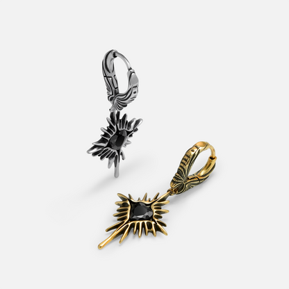 Silver and gold-tone Winged Heartburst hoop earrings arranged upright and flat with black heart stones