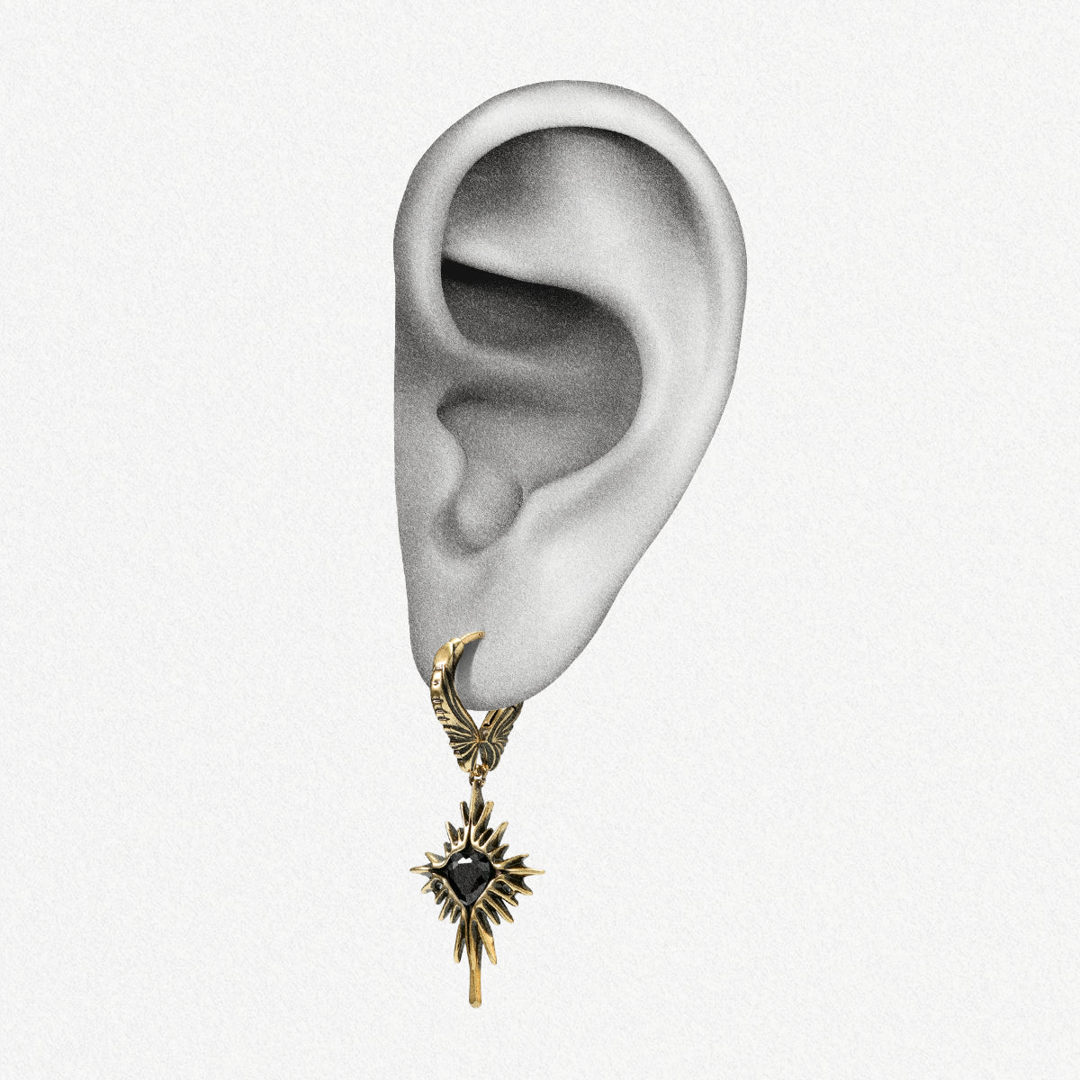 Gold-tone Winged Heartburst hoop earring positioned on an illustrated earlobe to show the full drop