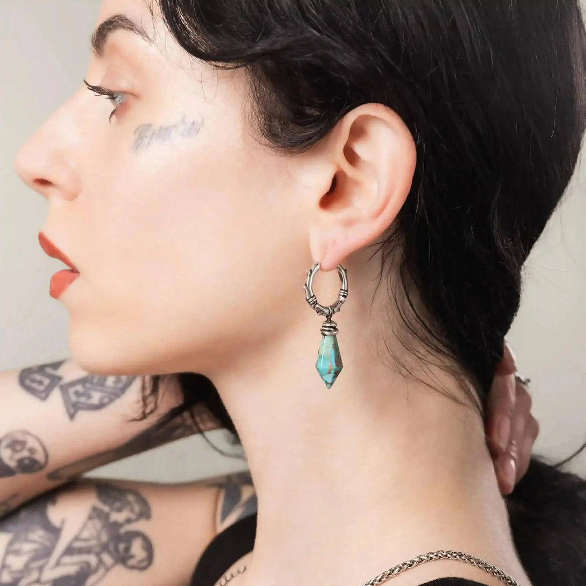 Wrapped Relic Earrings in 925 sterling silver, worn in side profile by a tattooed brunette, centering the turquoise relic dro