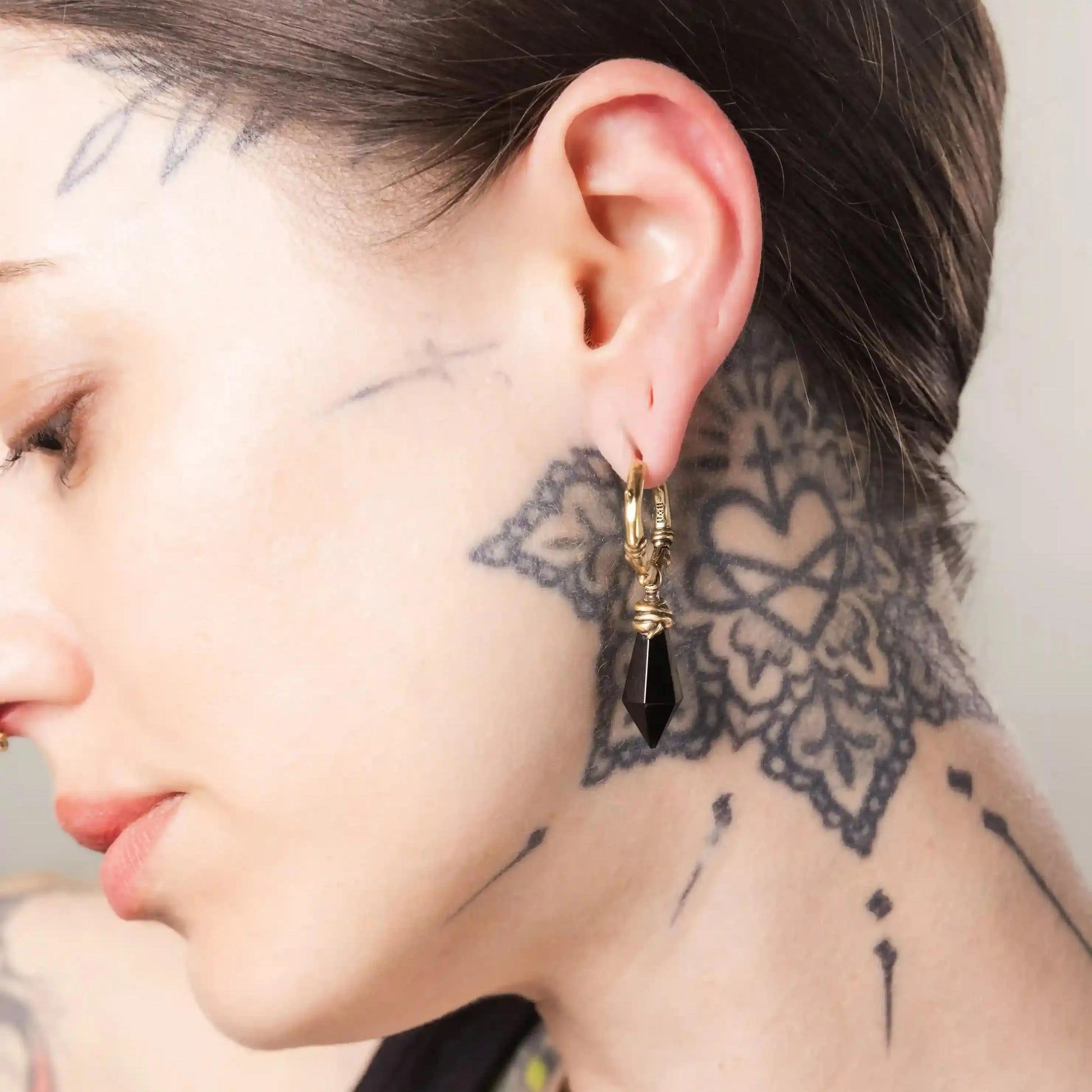 Model wearing gold Wrapped Relic Earrings with black obsidian drop stones and antiqued finish