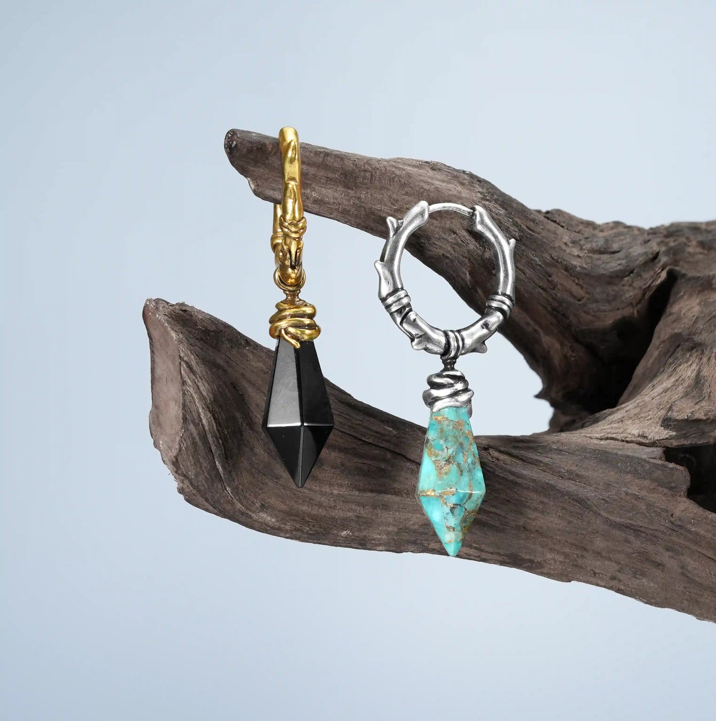 Wrapped Relic Earrings in silver and gold displayed on driftwood with raw stone drop details