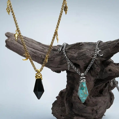Wrapped Relic Necklace in gold and silver displayed on driftwood with raw stone pendant details