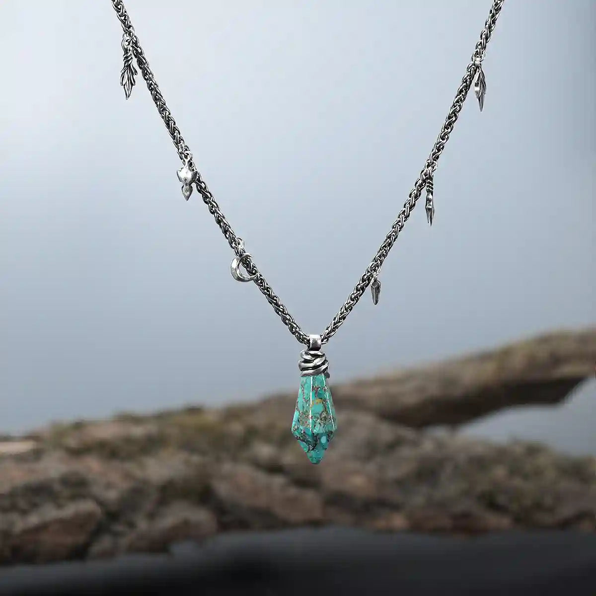 Turquoise Wrapped Relic Necklace displayed on wood with antiqued silver chain and charm details
